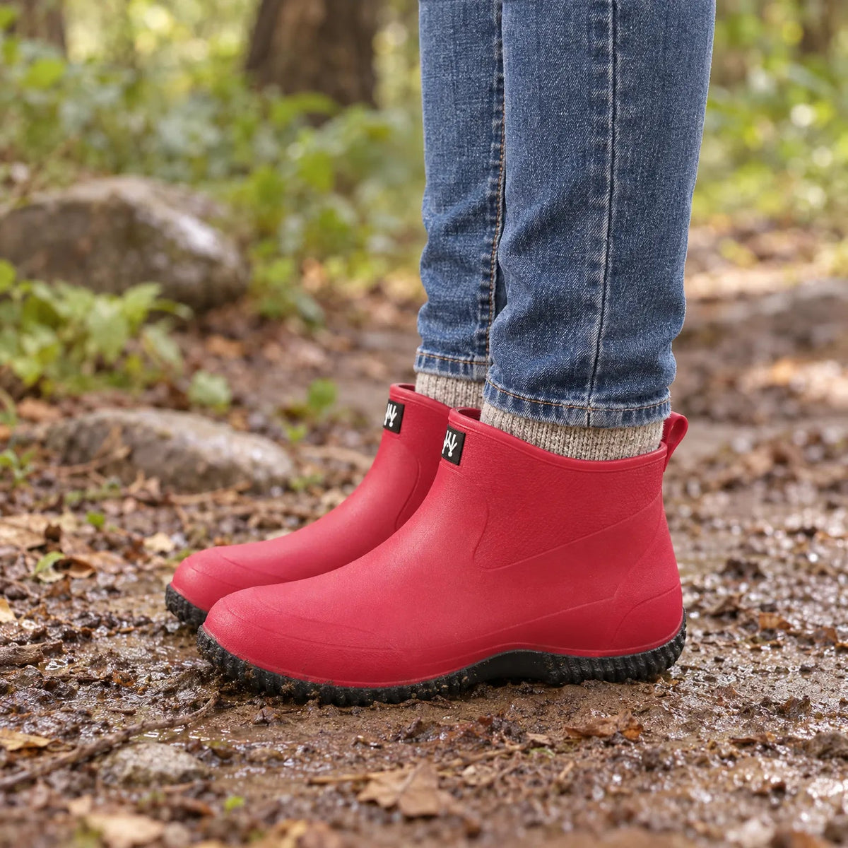 Kurze Gummistiefel Damen in Fuchsia getragen auf einem nassen Waldweg im Herbst