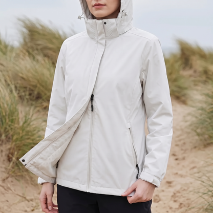 Frau in der weißen Damen-Windjacke mit aufgesetzter Kapuze in den Dünen bei Wind