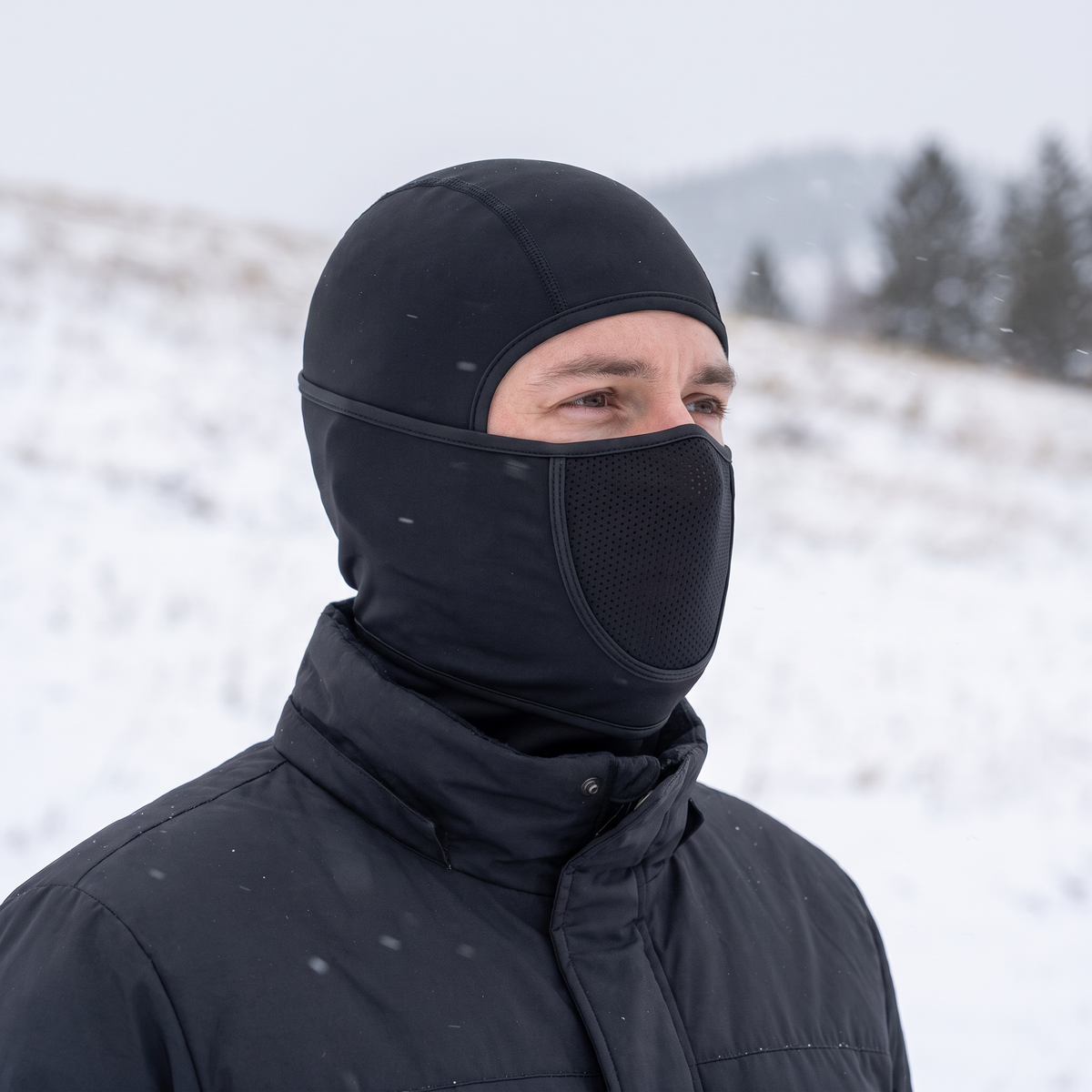 Mann trägt die schwarze Sturmhaube mit Mesh-Feld auf einem verschneiten Hang