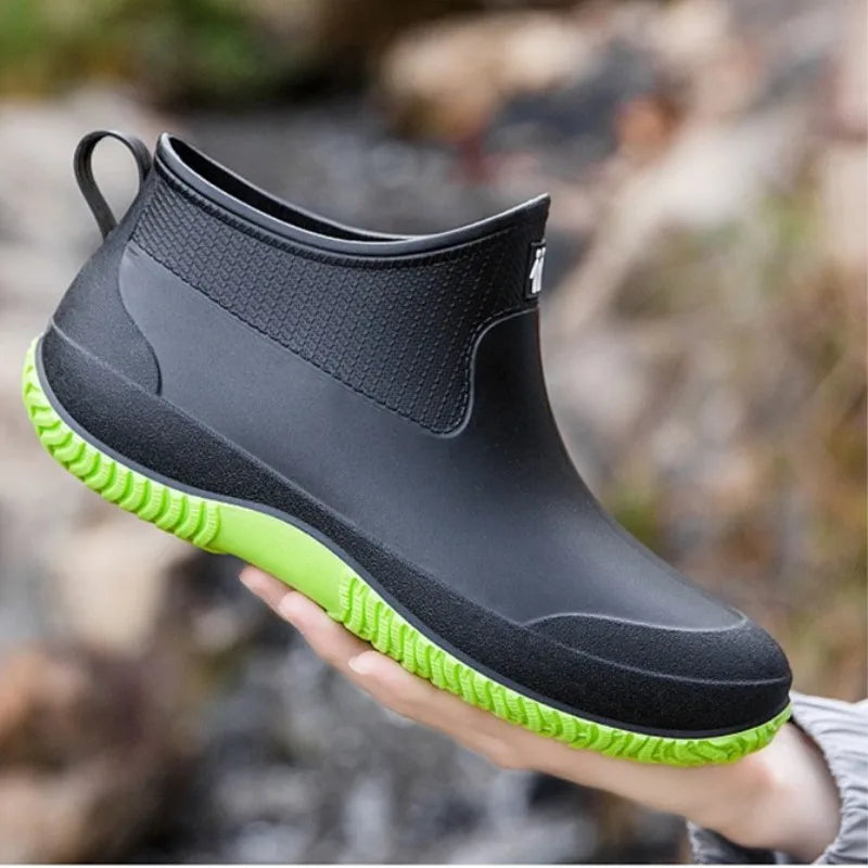Kurze Gummistiefel Damen in Schwarz mit grüner Sohle in der Hand