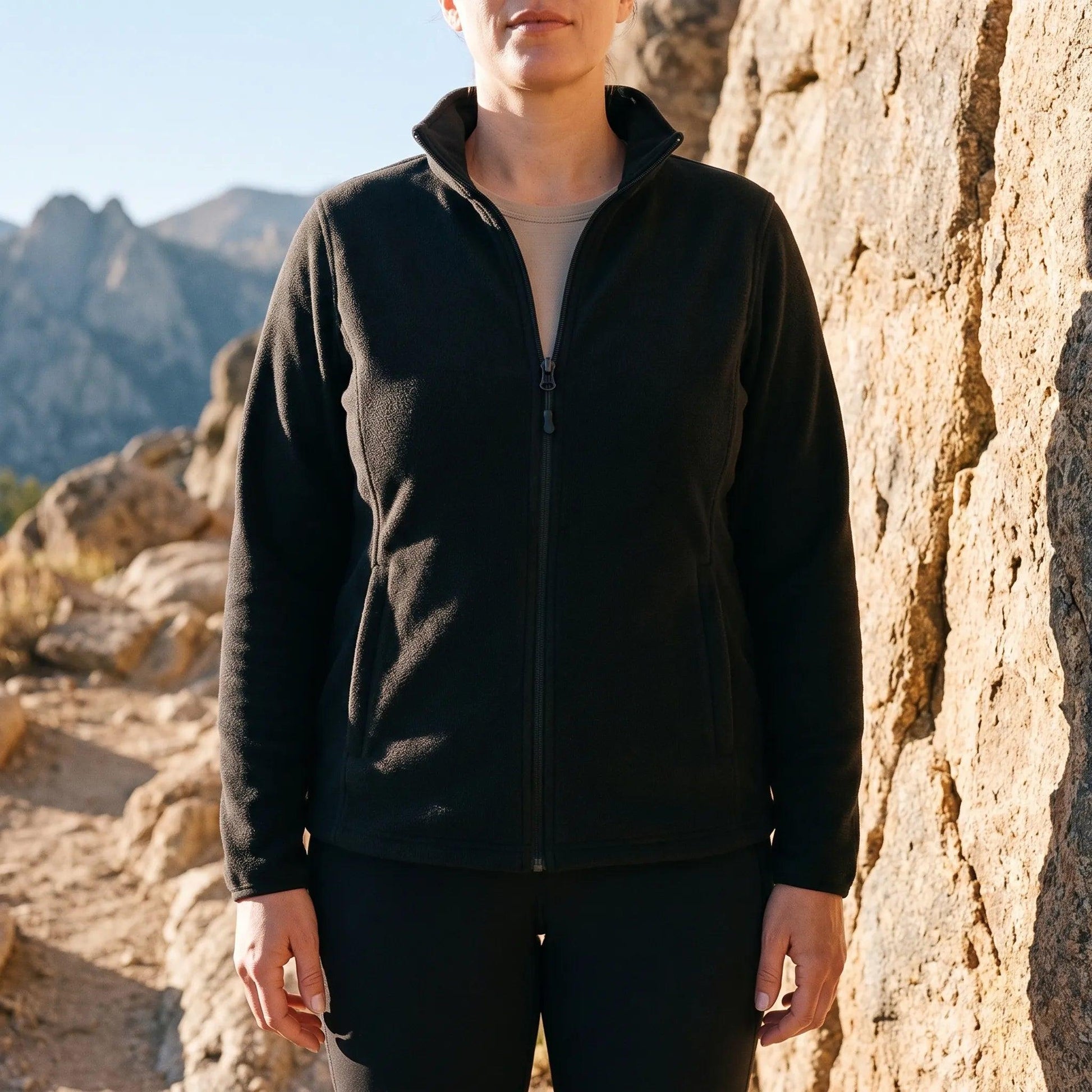Frau in der schwarzen Fleecejacke an einer Felswand