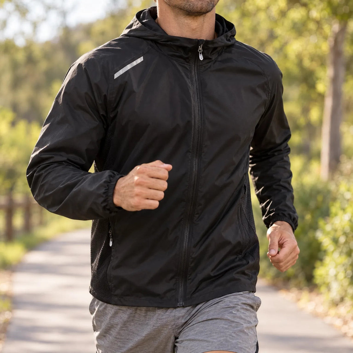 Schwarze Laufjacke Herren beim Training auf einem Waldweg getragen
