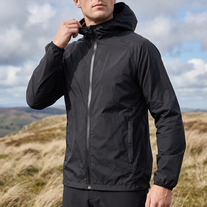 Mann trägt schwarze Windjacke auf einem windigen Hügelkamm